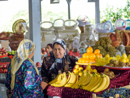 Zwei einheimisch Frauen aus Usbekistan unterhalten sich an einem Marktstand auf einem Basaar in Usbekistan.