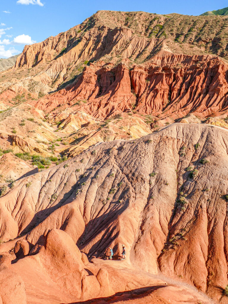 Der Märchencanyon oder Skazka Canyon in Kasachsten, fotografiert von einem erhöhten Punkt. Klein im Bild kann man eine Person erkennen, die gerade auf Wanderreise im Canyon ist.