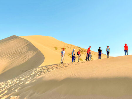 Mehrere Personen auf Wanderreise folgen dem Guide von Weltweitwandern über die singenden Dünen Altyn-Emel in Kasachstan.