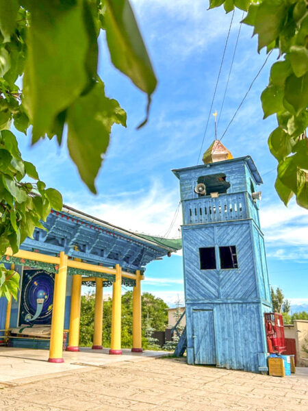Man sieht den blauen Turm der Dungan-Moschee in Kirgistan, sowie auch einige der gelben Holzsäulen des Hauptgebäudes.