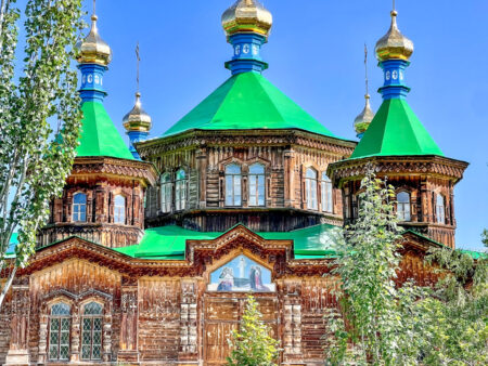 Eine russisch-Orthodoxe Kirche in Kirgistan, erkennbar an der Holzbauweise sowie den hohen grünen Türmchen.
