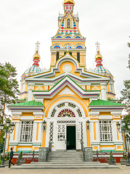 Das Bild zeigt die Himmelskathedrale oder Zenkov-Kathedrale in Almaty in Kasachstan. Das Gebäude besticht durch seine hohe Bauweise, gelben Wände und grünen Dächer.