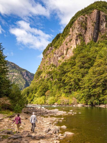 Zwei Personen auf einer Wanderreise gehen entlang eines Flusses in einem engen Tal in Patagonien in Chile.