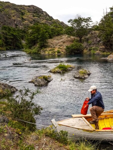 Ein Guide von Weltweitwandern steigt aus einem Ruderboot auf einem Fluss in Chile aus. Es handelt sich dabei um das Reserva Nacional Tamango.