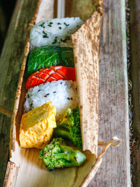 Eine Rolle aus Bambus, in die ein kleines Bento aus Gemüse, Ei und Sushi gepackt ist, die perfekte Wegzehrung für eine Wanderung in der Nähe des Mount Fuji.