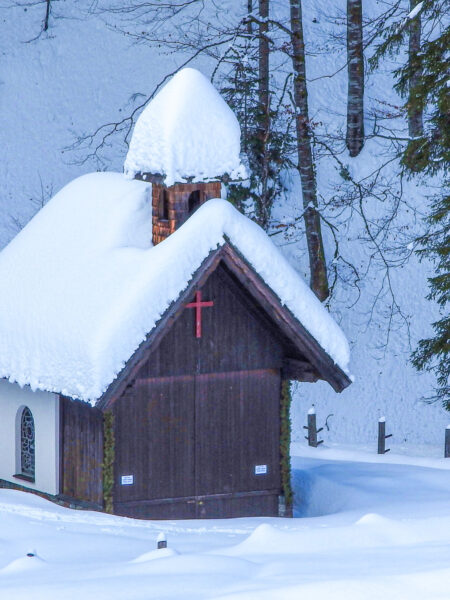 Am Foto sieht man die Rot-Kreuz-Kapelle am Hengstpass in den Kalkalpen. Sie ist bedeckt mit frisch gefallenem Schnee, der darauf wartet mit Schneeschuhen bezwungen zu werden.