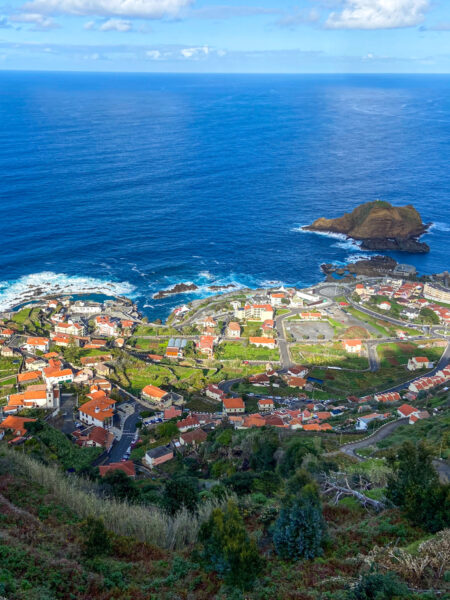 Man sieht die Stadt Porto Moniz an der Nordküste der Insel Madeira, von einem erhöhten Punkt auf der Insel aus, vermutlich von einer Wanderroute.