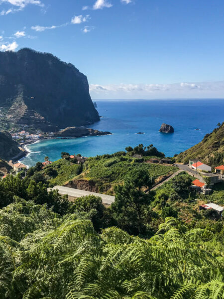 Ein Bild der Küste von Madeira inklusive mehrerer Gebäude im Vordergrund und dem strahlend blauen Ozean im Hintergrund.