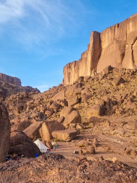 Auf dem Bild sieht man ein kleineres Zeltcamp im Jbel Sarhro, das halb hinter den Felsen versteckt ist.
