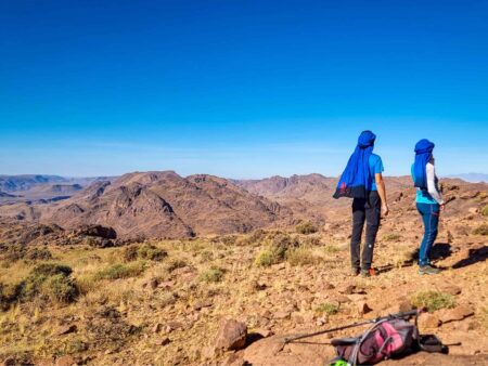 Zwei Wanderreisende genießen den Ausblick auf ihrer Trekkingtour durch Marokko. Vor ihnen breitet sich das Jbel Sarhro aus.