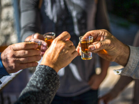 Mehrere Personen auf Wanderreise stoßßen mit Schnapsgläsern an. Sie sind auf einer Wanderreise in Montenegro, wo der heimische Schnaps bei einer Verkostung ausgeschenkt wird.