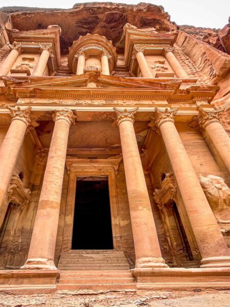 Auf dem Bild sieht man den Haupteingang von Petra in Jordanien, erkennbar an den hohen Säulen neben dem Eingang, die direkt aus dem Fels herauszuwachsen scheinen.