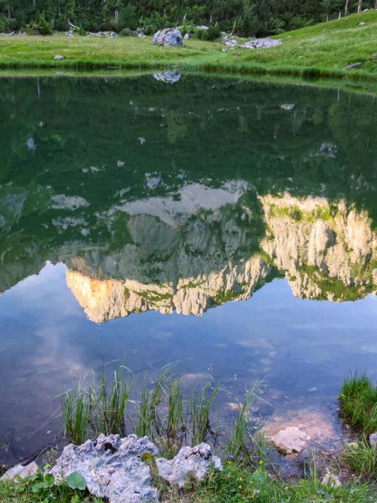 Man sieht die Spiegelung von Bergen im Nationalpark Kalkalpen in einem kleinen Bergsee, der auch im Zuge einer Wanderreise besucht werden kann.