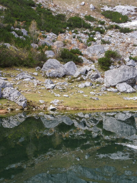 Das Bild zeigt einen Ausschnitt des Brunnsteiner Sees mitten im Bergparadies Warscheneck. Die schroffen Felsen, die so gängige sind im Nationalpark Kalkalpen, spiegeln sich auf der Wasseroberfläche.