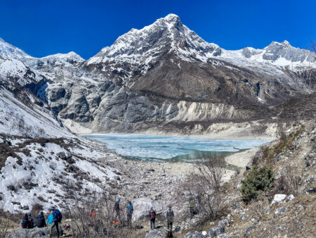 Auf dem Bild sieht man den Birendrasee im Himalaya. Mehrere Wanderreisende machen Rast in der Nähe seines Ufers.