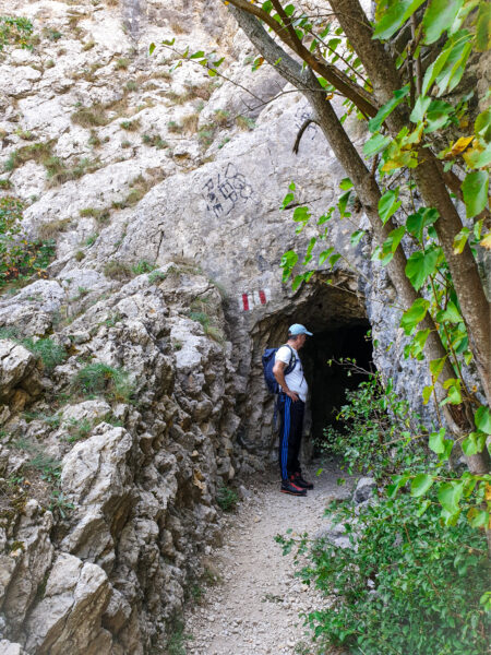 Ein Wanderer auf seiner Reise durch Rumänien steht vor dem Eingang eines der vielen Tunnel, die in der Schlucht des Flusses Nera in den kalkhaltigen Stein der Region gehauen wurden.