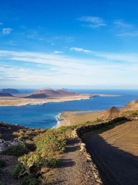 Man sieht den spektakulären Ausblick von Lanzarote auf die kleinere Nachbarinsel La Graciosa von einem Wanderweg auf der Atlantikinsel aus.