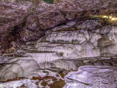 Wir sehen Teile der Kaklikhöhle in der Türkei. Sie befindet sich in der Nähe von Pamukkale und ist gekennzecihnet durch die Kalkformationen und das bunte Gestein, das zu Teilen darunter zu erkennen ist.