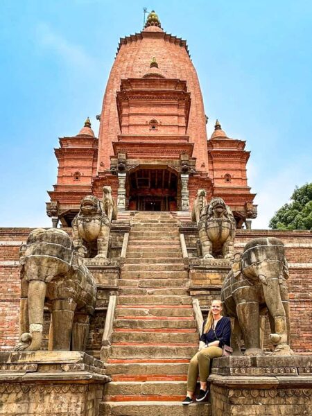 Eine junge Frau auf einer Wanderreise in der Region Langtang in Nepal sitzt auf den Stufen zu einem Tempel in Bhaktapur.