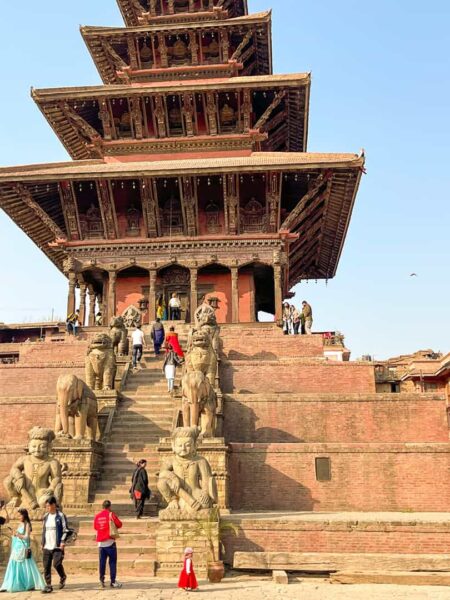 Mehrere Personen einer kleinen Reisegruppe von Weltweitwandern stehen auf den Stufen zu einem Tempel in Bhaktapur.