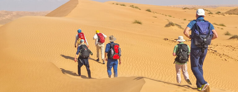Mehrere Personen wandern durch die Wüsten des Oman.