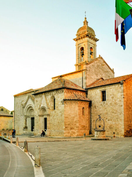 Die Collegiata-Kirche von San Quirico d'Orcia ist auf dem Foto im Licht der toskanischen Abendsonne zu sehen.