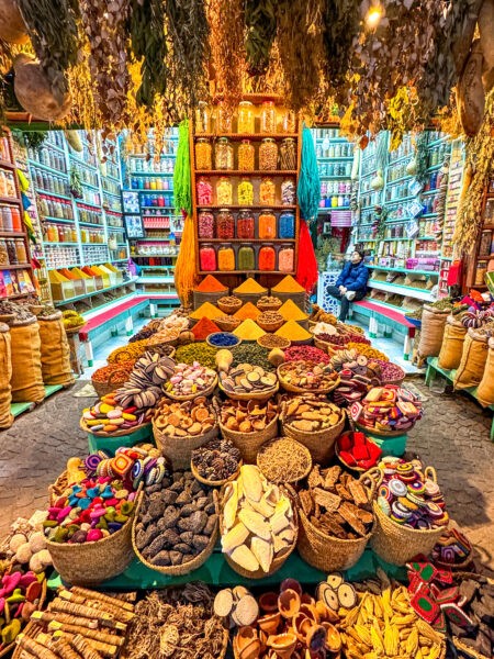 Ein Geschäftslokal in einer Stadt im Südwesten von Marokko. Im Inneren kann man Unmengen an Gewürzen sehen und einen Einheimischen, der auf einem Stuhl in dem Geschäft sitzt.
