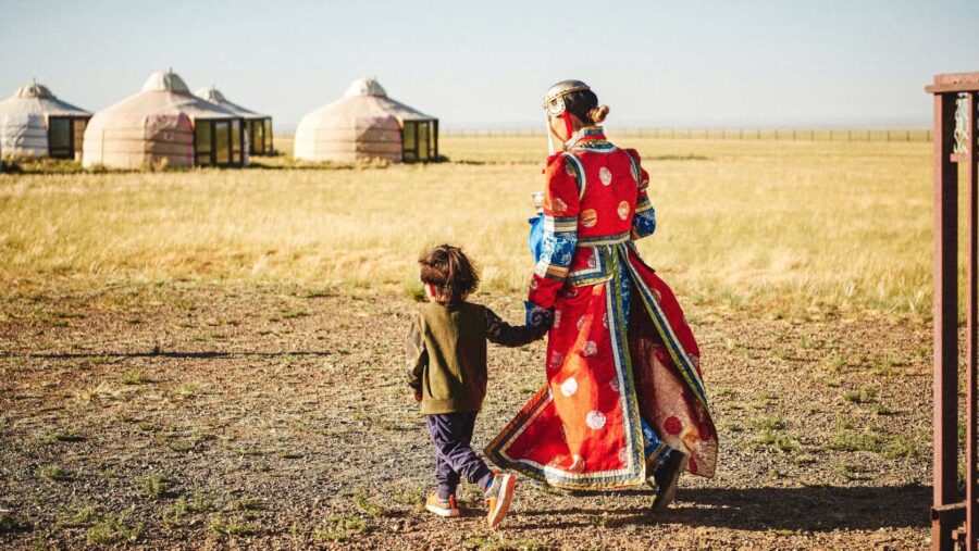 Mongolei, traditionell gekleidete Frau mit Kind am Weg zu einer Jurte