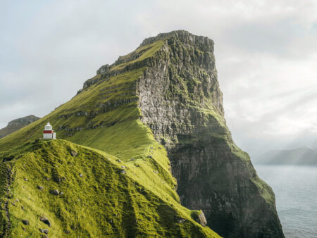 Eine steile Klippe an der Küste der Färöer-Ineln ragt über den harschen Atlantik hinaus und kann im Zuge einer Wanderreise mit Weltweitwandern erklommen werden.