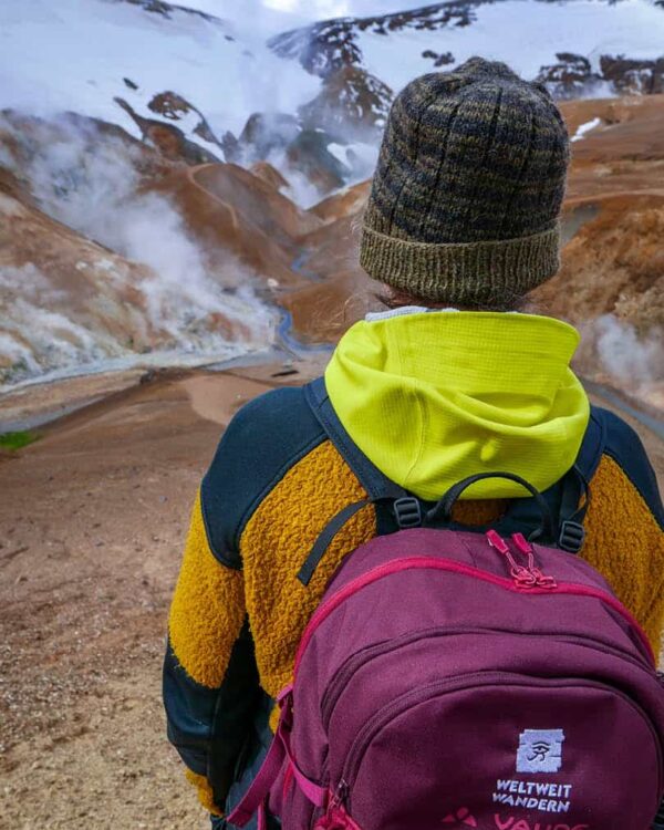 Jemand mit einem Weltweitwandern-Rucksack steht im Kerlingarfjöll Heißquellengebiet in Island.