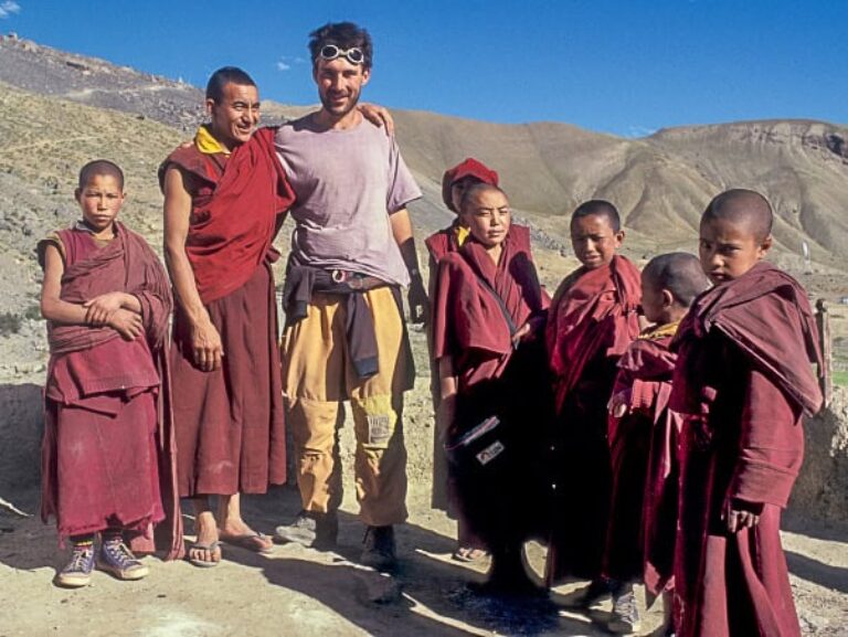 Christian Hlade steht mit mehreren jungen Mönchen in traditioneller Kleidung in einer Gebirgslandschaft in Ladakh