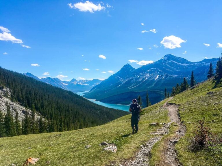 Wanderer auf einem Bergweg in Kanada mit Blick auf türkisfarbenen See, Wälder und Rocky Mountains