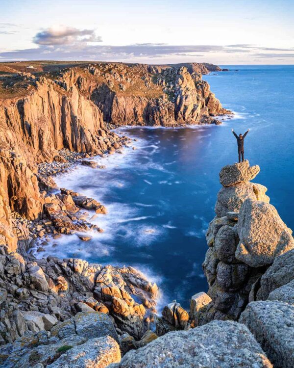 Ein Wanderer steht auf den Klippen von Cornwall und schaut aufs Meer hinaus.