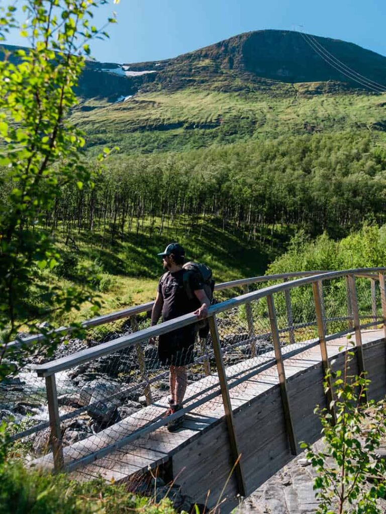 Ein Mann wandert über eine Brück in Nordnorwegen.