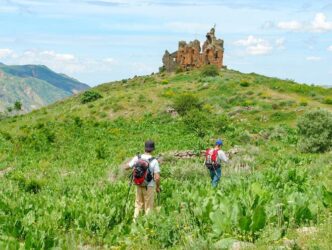 Zwei Personen wandern auf die Ruinen eines armenischen Klosters zu.