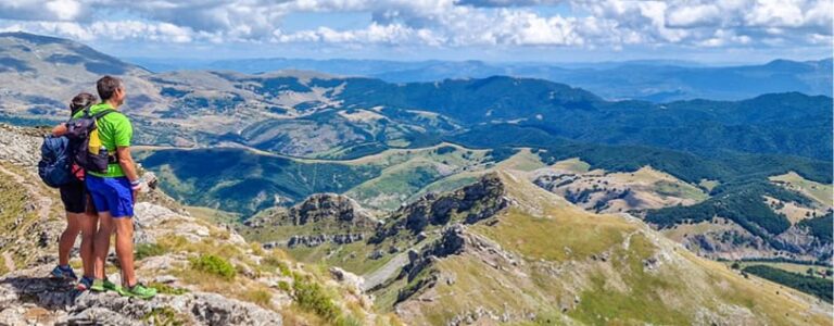 Ein Ausblick über das Bergland in Bosnien mit einem Pärchen beim Wandern.
