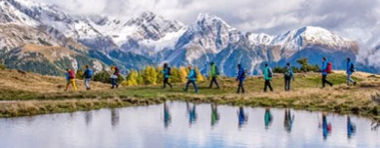 Eine Wandergruppe hinter einem Bergsee im Lesachtal.